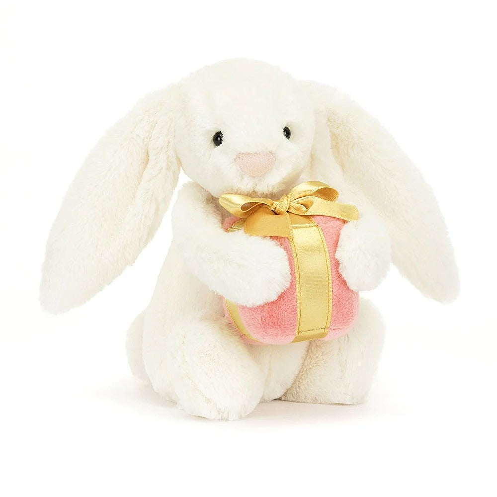 A classic gift to share love and joy with iconic Bashful Bunny. This cloud-soft bunny has cream fur, floppy ears and a pink suedette nose. Holding a sumptuous pink present with gold satin bow, this Bashful Bunny is the perfect cuddly gift that keeps on giving! Dimensions: 7" x 4".