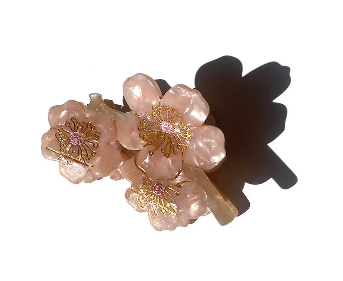 Add a touch of floral elegance to your hairstyle with this Cherry Blossom clip. It is double sided for a perfect look from every angle. Unlike most plastic accessories, these small-batch styles are made from a biodegradable wood pulp acetate, making these clips both beautiful and kind to the environment! Size: 3"x 1.5"