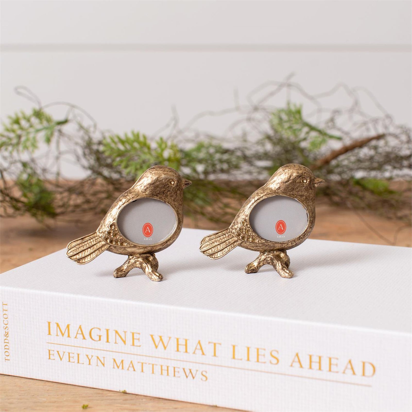 A miniature gold colored photo frame, shaped like a bird, on a white background.
