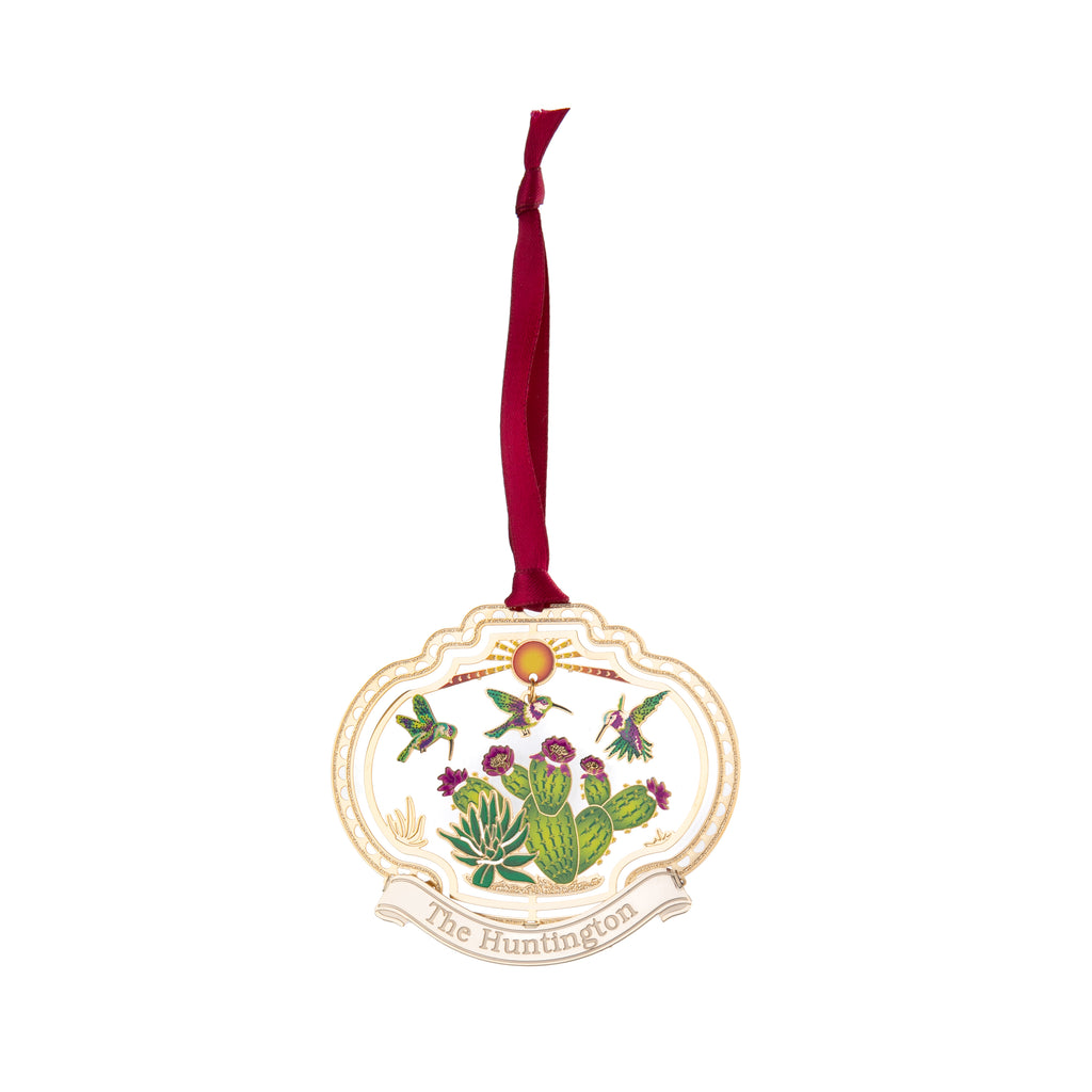 This etched brass ornament is one of a collection of four which depict colorful vignettes from around the Huntington's beloved gardens.   From the desert garden, three hummingbirds dance around the flowers atop a prickly pear cactus. Finished in 24k gold with hand-lacquered color. Exclusive to the Huntington Store.