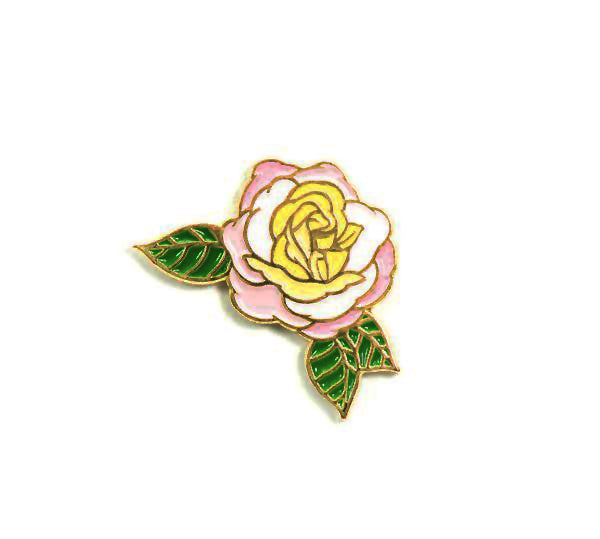 Enamel pin featuring the 'Huntington's 100th' rose, in celebration of the centennial of The Huntington. This rose has pastel yellow tones with a kiss of orchid pink and cream and the fragrance of citrus blossoms and sweet fruit. Hybridized by Tom Carruth, The Huntington's Curator of the Rose Collections. Size:1"x 3/4".