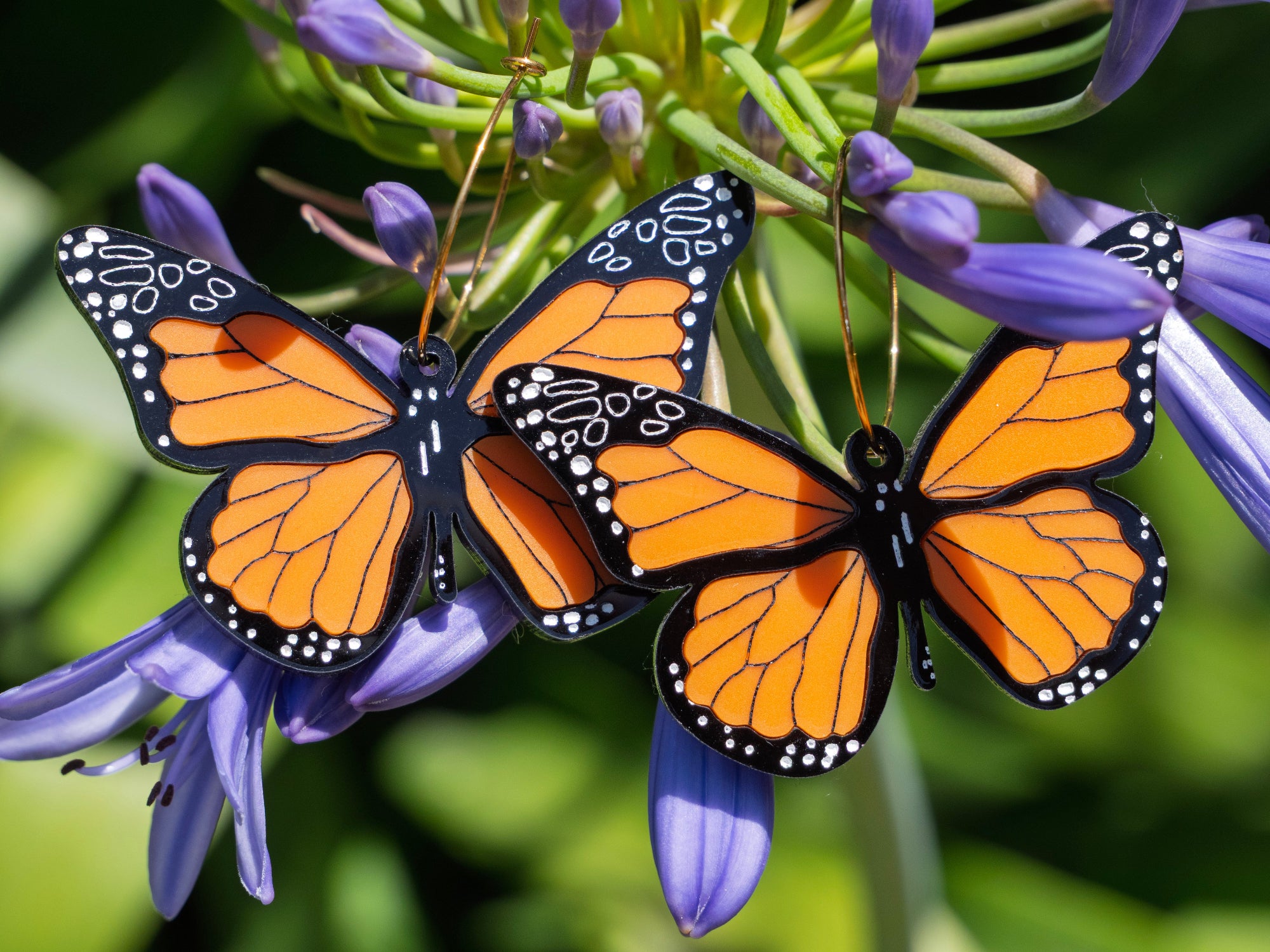 Add a fluttering flourish to your outfit with these striking Monarch Butterfly earrings. These lightweight and fun earrings are made from laser-etched acrylic, with hand painted details, giving them a three-dimensional effect. The hoops are made from 18k gold plated stainless steel, making them safe and comfortable to wear. 