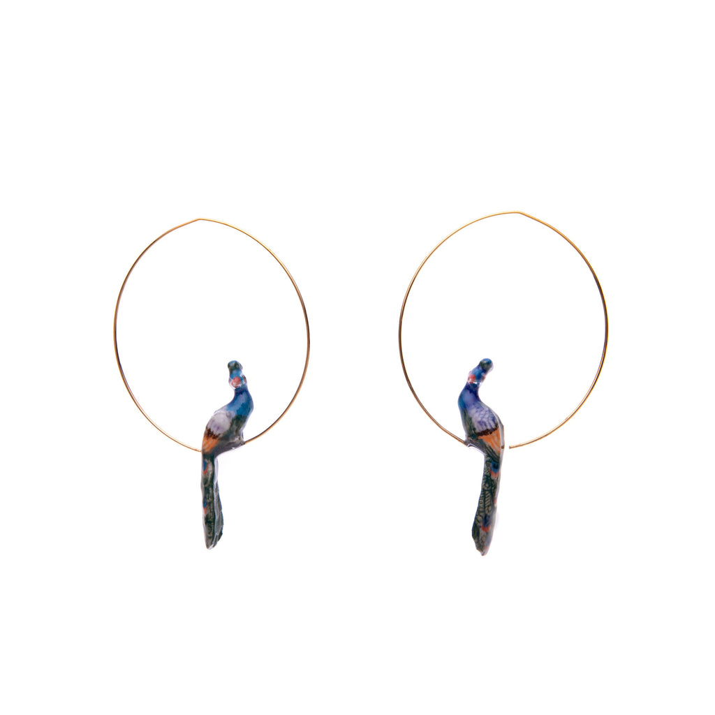 These pretty hoop earrings feature a peacock perched on a gold hoop. Made from durable, lightweight porcelain and gold-plated stainless steel. The porcelain elements are individually painted by hand. Lead and nickel-free Material: Porcelain & Gold-plated stainless steel Dimensions: Approx. 2.5" length, 1.3" peacock