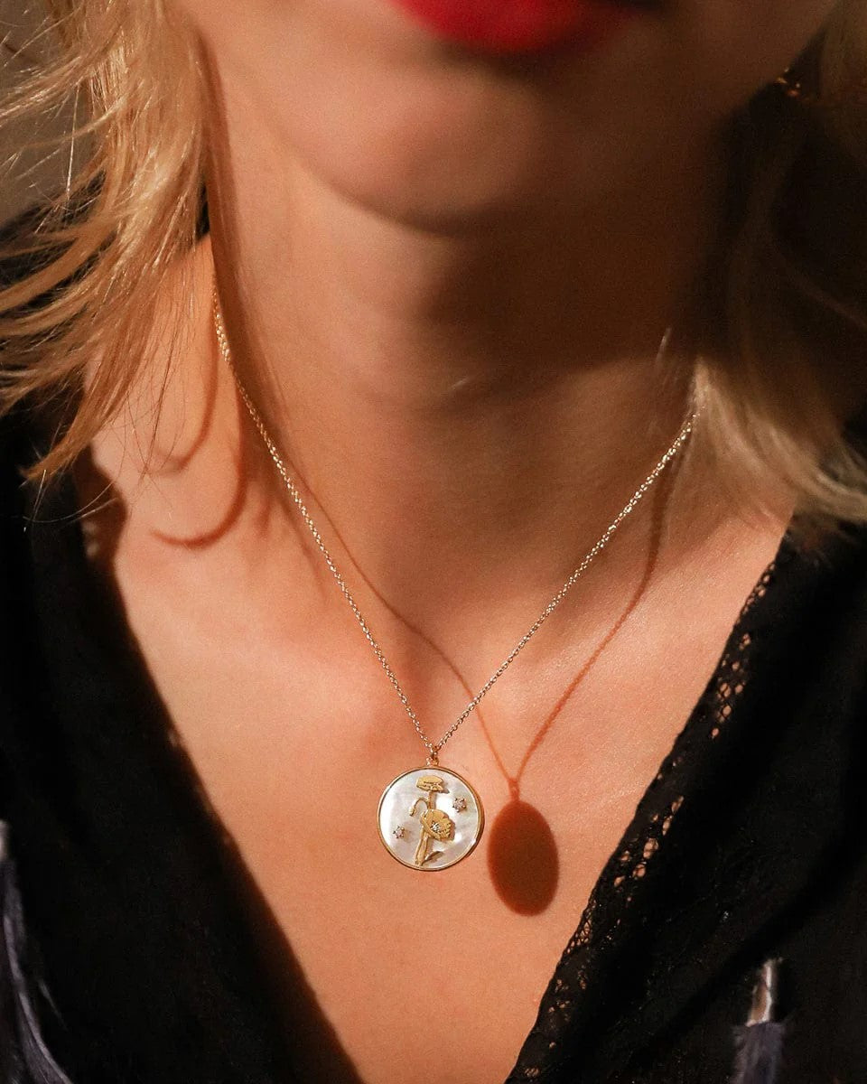 This Mother of Pearl Flower Pendant necklace has CZ detail, gold plating, and a mother of pearl coin pendant featuring flowers that are as pretty as the real thing! Wear with layers of gold necklaces or on its own. Materials: Gold-Plated Brass, Mother of Pearl, CZ Dimensions: 16-18" length Lead, Nickel-free