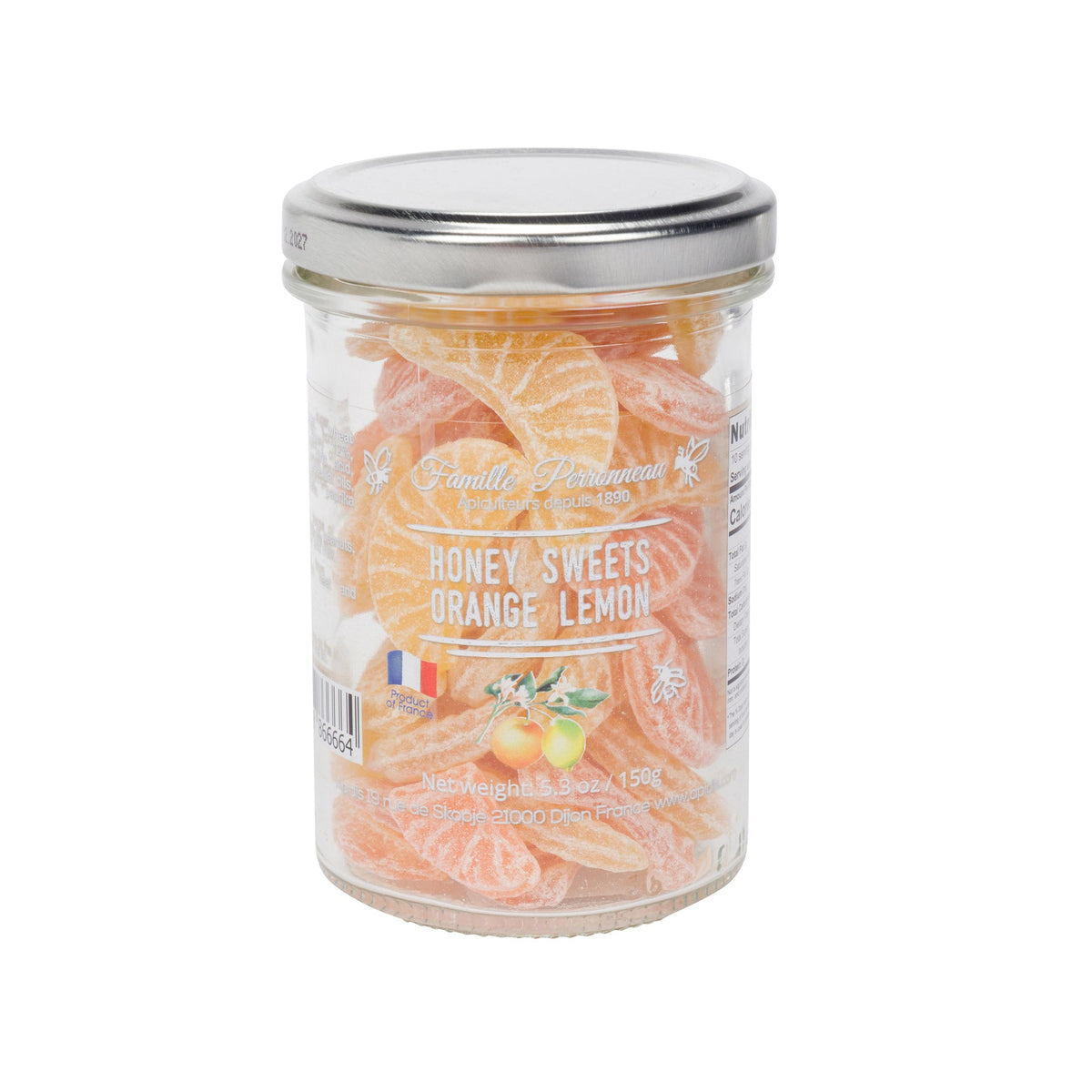 A glass jar of Famille Perrissonne Honey Sweets Orange Lemon, filled with orange and yellow citrus-flavored candies, topped with a silver metal lid, on a white background.