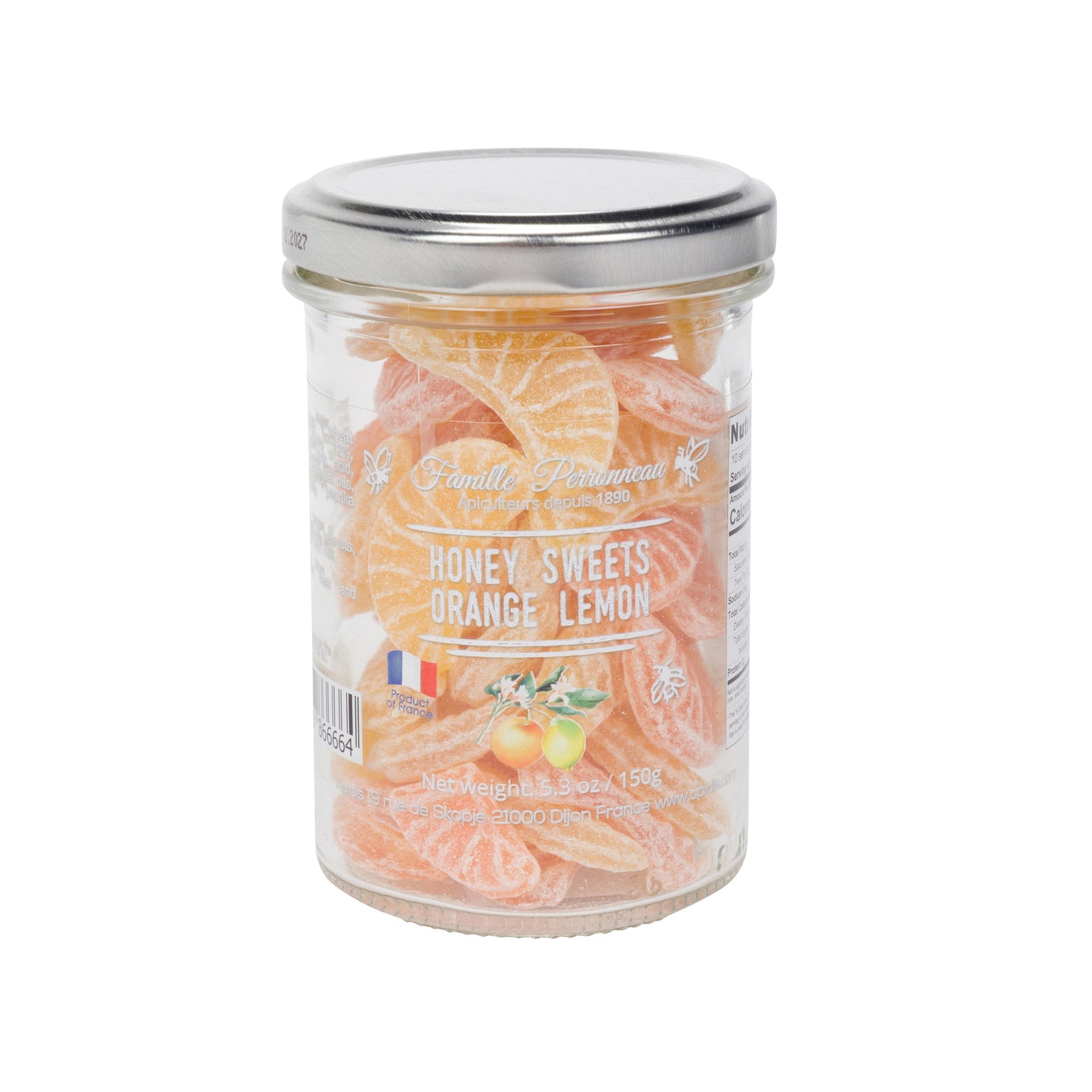 A glass jar of Famille Perrissonne Honey Sweets Orange Lemon, filled with orange and yellow citrus-flavored candies, topped with a silver metal lid, on a white background.