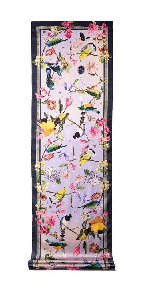 This beautiful, long-length scarf is a true wearable work of art. The vibrant print shows colorful birds, perched on branches and dancing around pink, lilac and ivory blossoms. This is the perfect scarf to carry in your purse as a quick cover-up. Dimensions: 19" x 72" Material: Silk satin polyester.