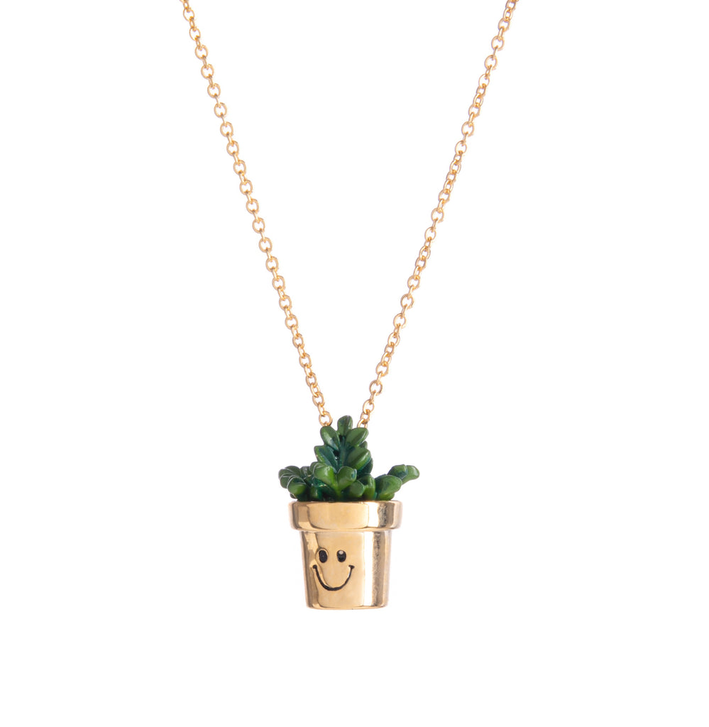 Love plants? Then you'll love this cute and quirky little planter necklace. Sweet in design with its smiling gold planter and green enamel leaves, this pendant necklace is a must-have for green thumbs. Can be worn at any length up to 16.5". Pendant - width 6mm x height 19mm Materials: 14ct gold plated brass, enamel.