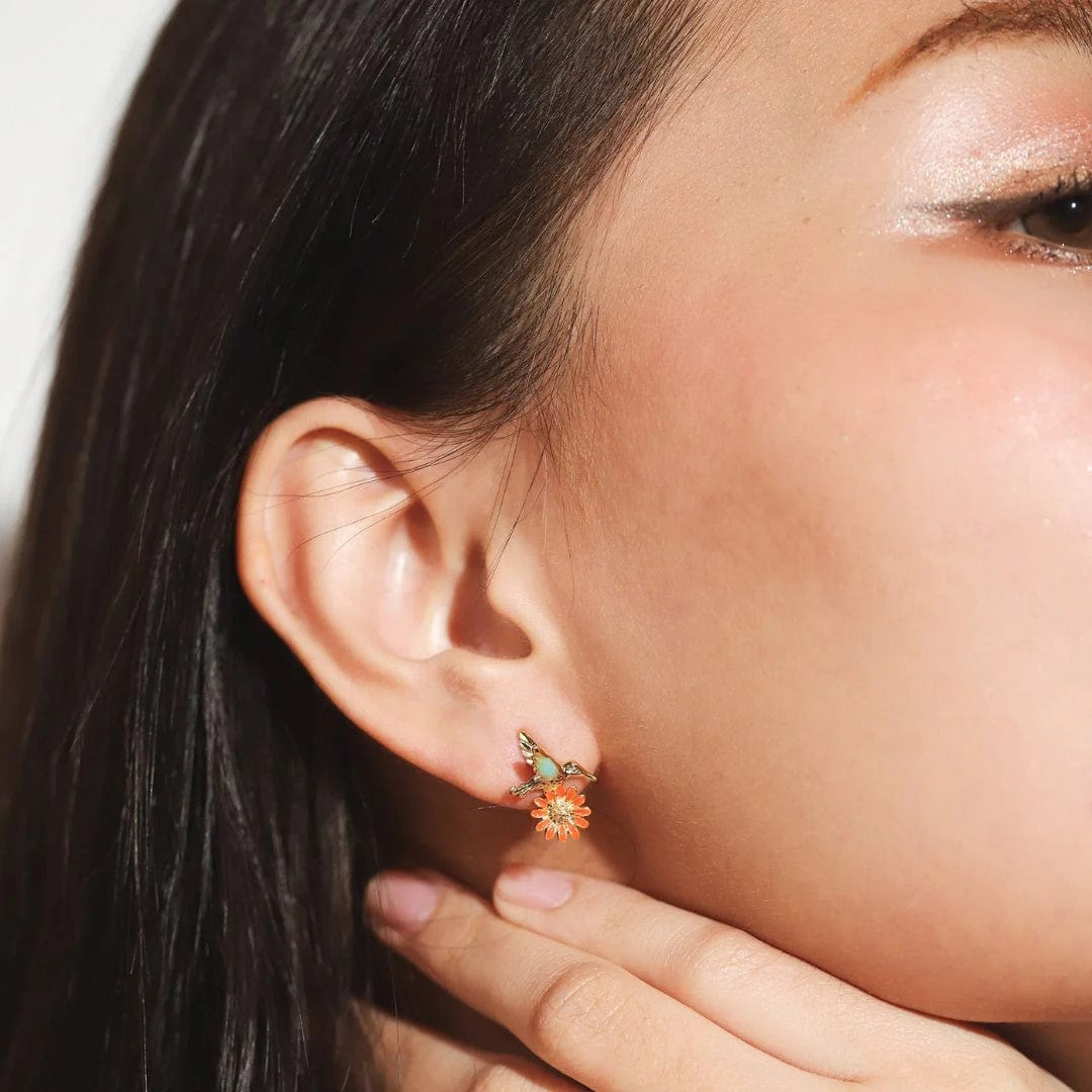Infuse some whimsy into your jewelry collection with these Hummingbird and Daisy stud earrings. Made from titanium with a pretty red flower detail, these are durable and pretty enough for daily wear. A great gift for bird and nature lovers alike. Material: Titanium, Enamel Dimensions: 0.5" x 0.5" Lead and Nickel-free