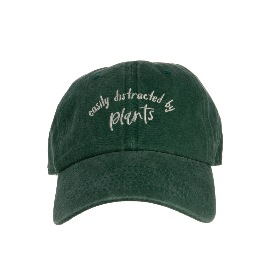 This soft, washed green baseball cap is perfect for, avid gardeners, yoga class devotees, golfers, dog walkers, runners and more! Featuring whimsical 'easily distracted by plants' embroidery on the front and embroidered potted plants at the back. Adjustable metal buckle. Materials: Cotton, Metal One size fits most.