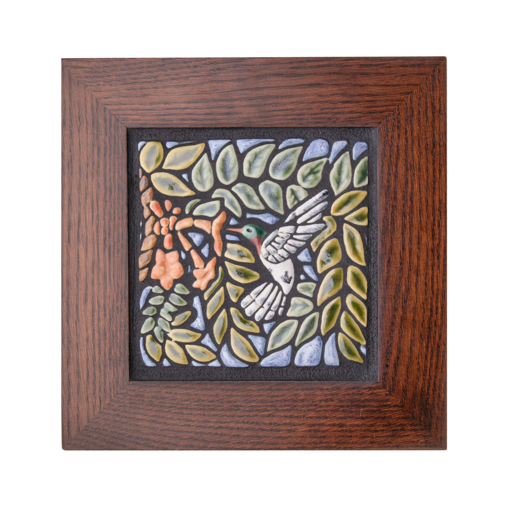 Expertly handcrafted in an artisan workshop in Canton, Ohio, this delightful ceramic tile features a colorful relief of a hummingbird in flight, sipping from a pretty coral flower. The tile is surrounded by a high quality, 1.5" quarter sawn oak frame. Has a notch in the wood frame for easy hanging. 10" x 10".