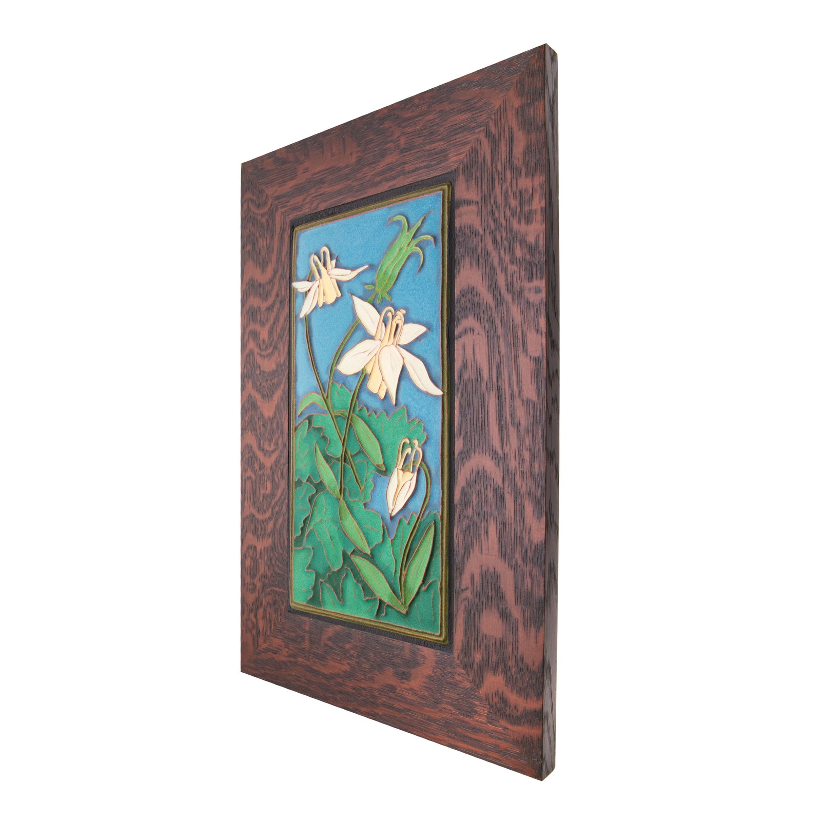 Expertly handcrafted in an artisan workshop in Portland, Maine. This ceramic tile features a relief of a Columbine flower against an early evening sky. The tile is surrounded by a 2.5" quarter sawn oak frame. Each tile carries the artist's stamp and has a brass picture hook at the back. Size including frame: 17" x 11" 