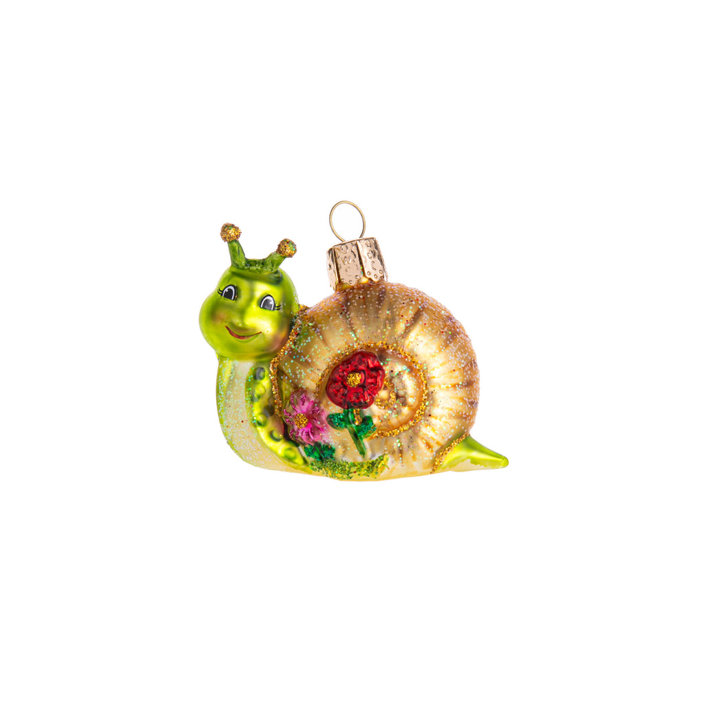 This smiley snail glass ornament is here to remind you of the beauty of taking it all in. This hand-decorated glass ornament has glitter detail, and flowers on its shell. Bring in a touch of nature to your home and holiday decor with this ornament. Dimensions: 2.5" x 2" Hand-decorated glass ornament