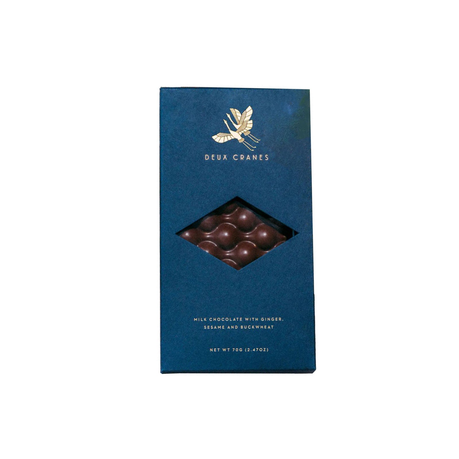 A tall, dark blue chocolate bar with a diamond-shaped window showing milk chocolate balls inside. The box features a gold logo of a winged figure and the brand name 'Deux Crânes' in gold text.