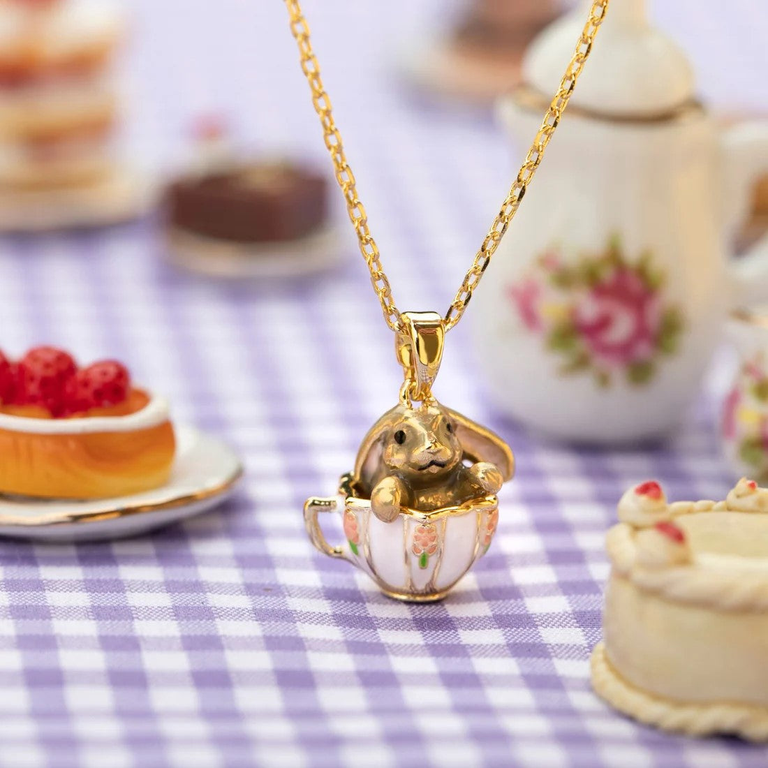 This bunny in a teacup is the perfect necklace for a tea party and is small enough for daily wear. With floral detail on the teacup and the cute bunny peeking out, this necklace will add whimsy to any outfit. Material: Gold-plated Brass, Enamel Dimensions: Approx. 16" Length with 2" Extender Lobster Claw Clasp