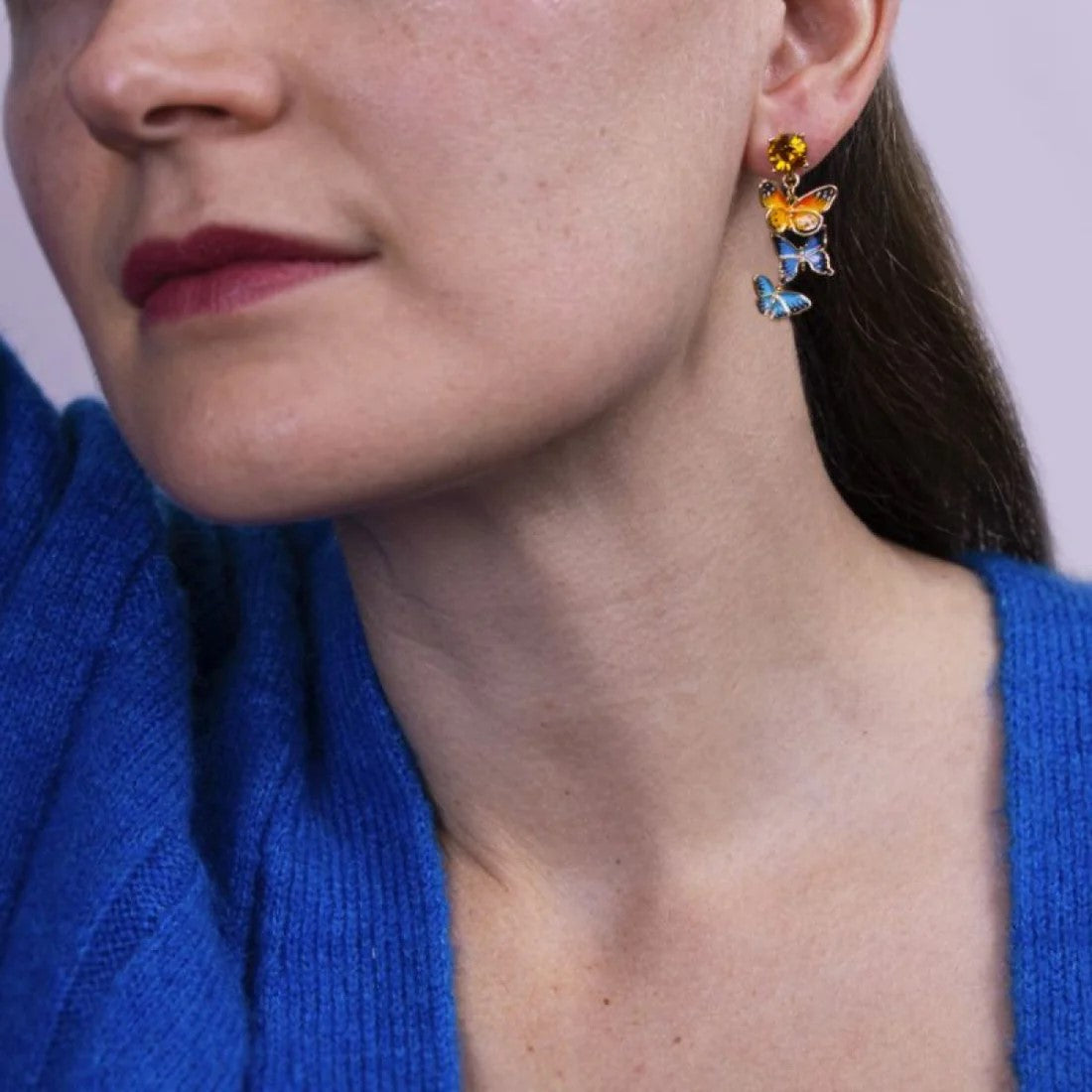 These cascading blue and orange butterflies are stunning for a statement earring that will add whimsy to your outfit. With a crystal post, these have sparkle and nature. Grab these for a colorful pop of these bedazzling bugs. Material: 18ct Gold-plated Brass, Enamel Dimensions: Approx. 0.6" W x 1.4" L Stud post
