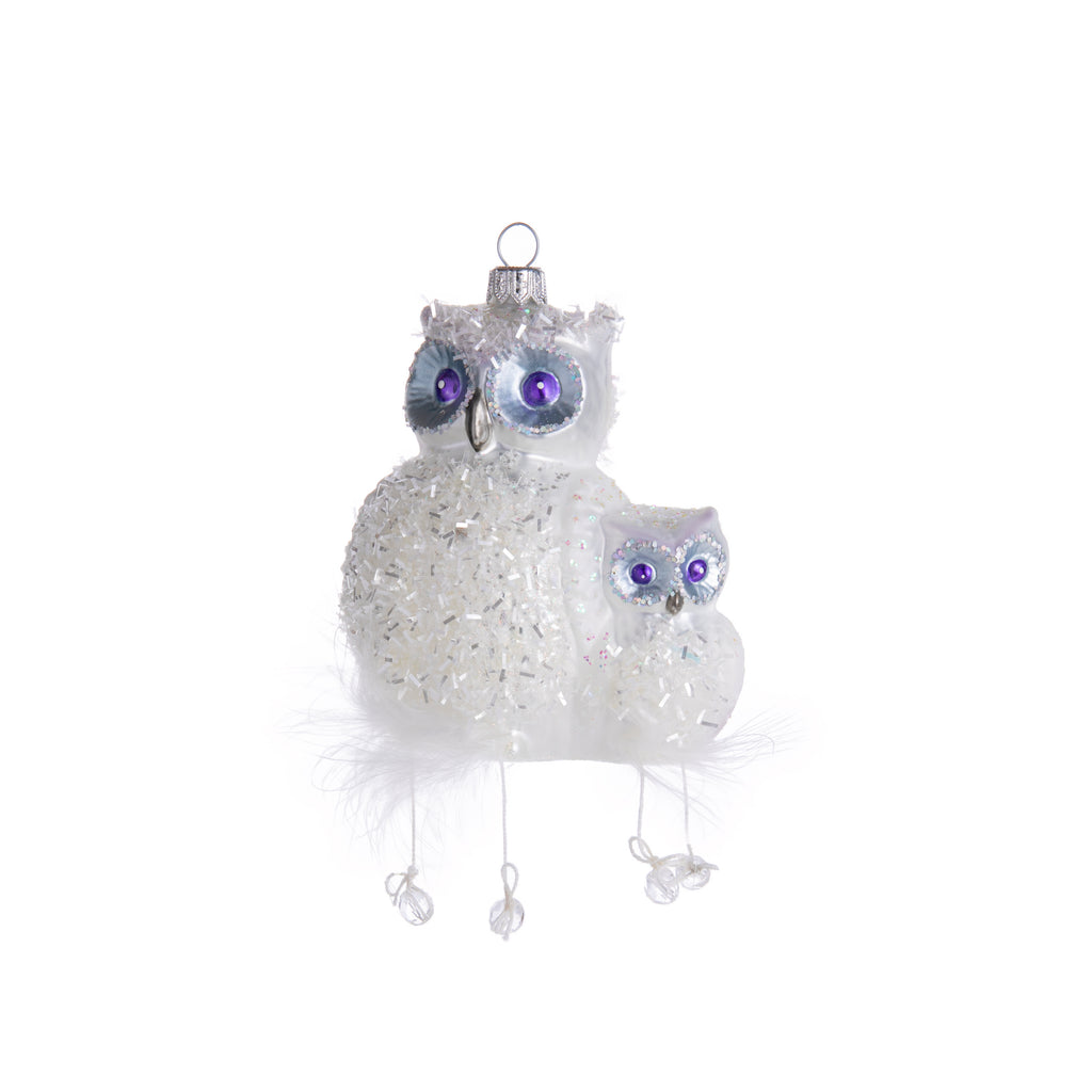 Even though these raptors are typically night birds, this glass ornament featuring glistening owls will shine day or night. Hand-decorated with glitter and tinsel, this mama and baby owl have feathers and crystals hanging from them as well as bright purple painted eyes. Dimensions: 6" H x 3.5" 