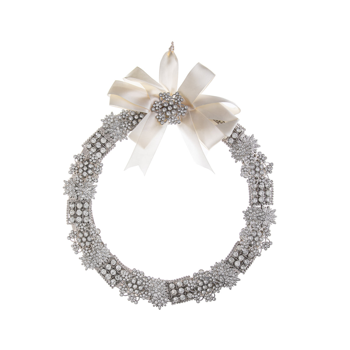 This wreath bejeweled in silver and vintage-style crystal brooches is gorgeous to elevate your home or holiday decor. With a satin ivory bow adorning the top, and tons of sparkle, this wreath would be beautiful anywhere to evoke antique glamour. The bow also has a loop for hanging. Dimensions: 10.5" Diameter