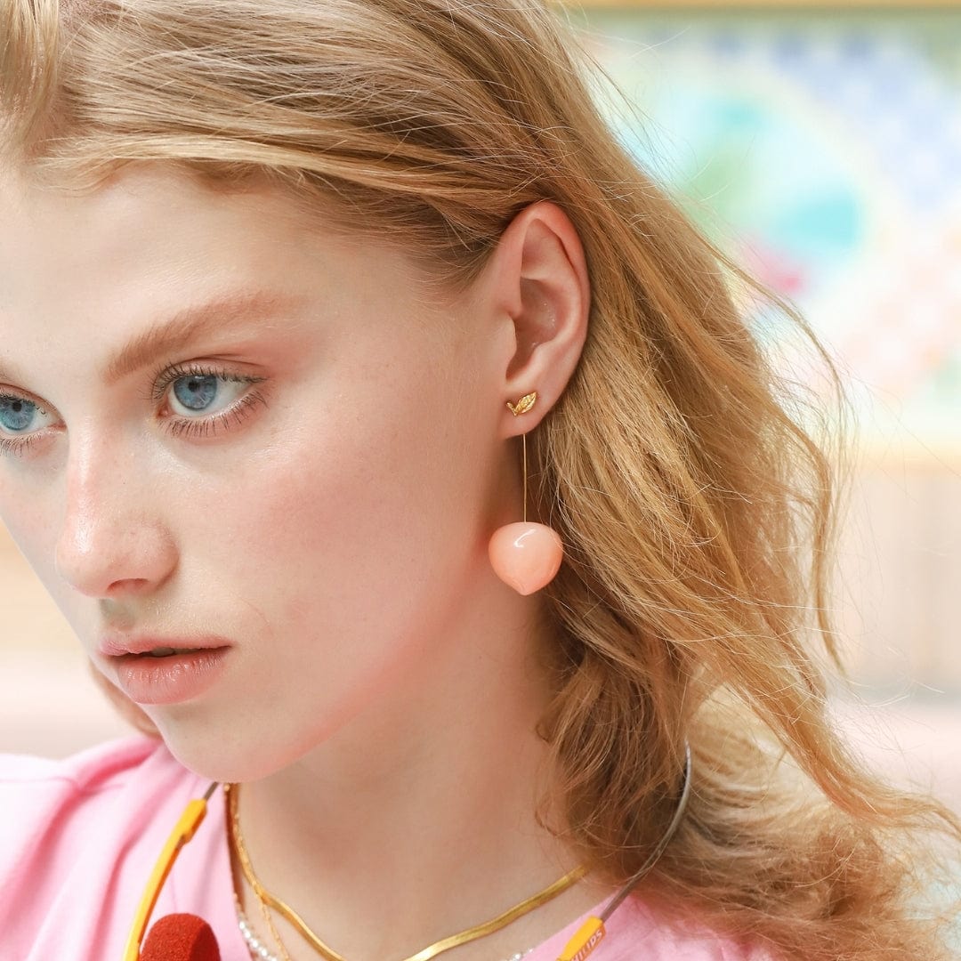 Hanging from golden leaf studs, these cute resin peaches dangle from your ears with the utmost charm. Perfect for a picnic, or a sweet evening out, these are great for adding some eclectic appeal to any outfit. Material: Brass, Resin Dimensions: Approx. 2" Length, 0.8" Width Wire drop closure Lead and Nickel-free