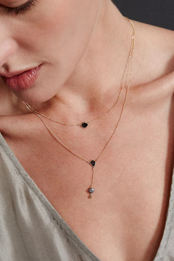 Subtlety meets glamour in this understated but very elegant lariat necklace. Featuring a freshwater peacock pearl at the bottom with a tiny white diamond, this lariat necklace also boasts a very unique black diamond slice situated just above. On a delicate 14k gold chain.