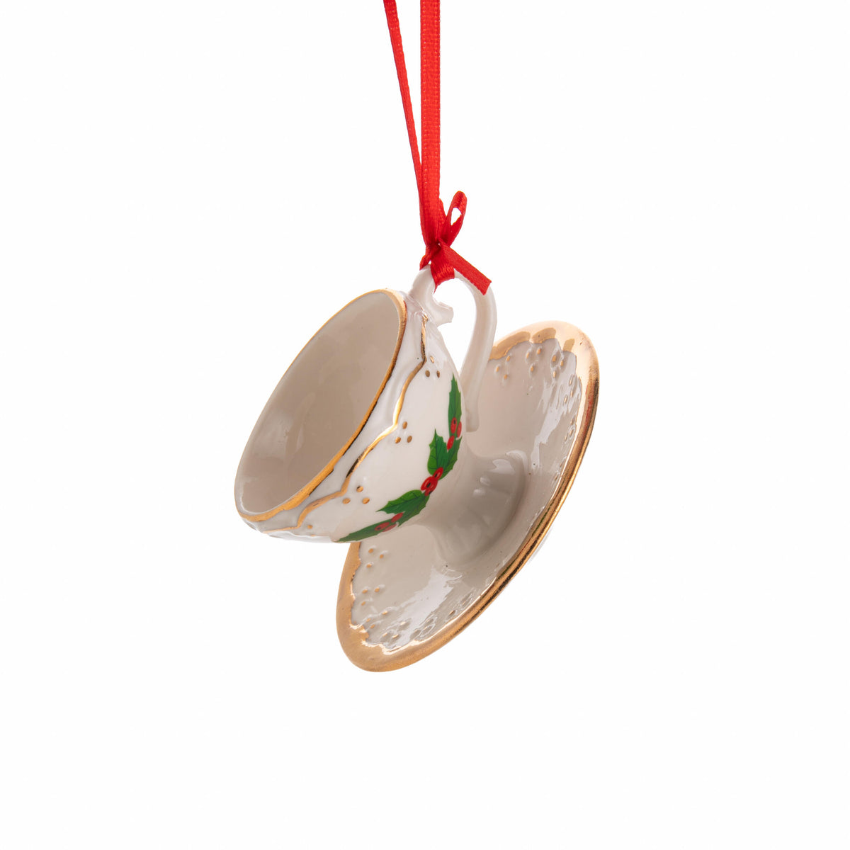 Decorative ceramic teacup and saucer ornament with holly design on a white background