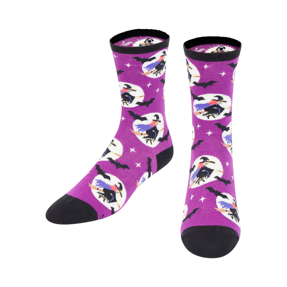 A pair of purple crew socks with a Halloween-themed pattern featuring witches on broomsticks, crows, bats, and stars, with black heels, toes, and cuffs.