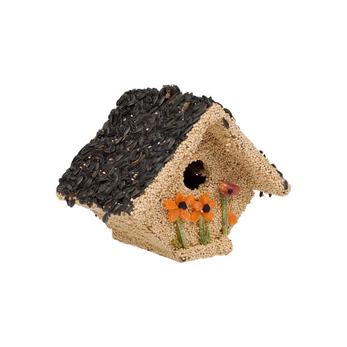 A small decorative birdhouse crafted from sunflower seeds, featuring a dark seed-covered roof, a beige seed-textured body, a round entry hole, and three small orange flower accents on the front, isolated on a white background.