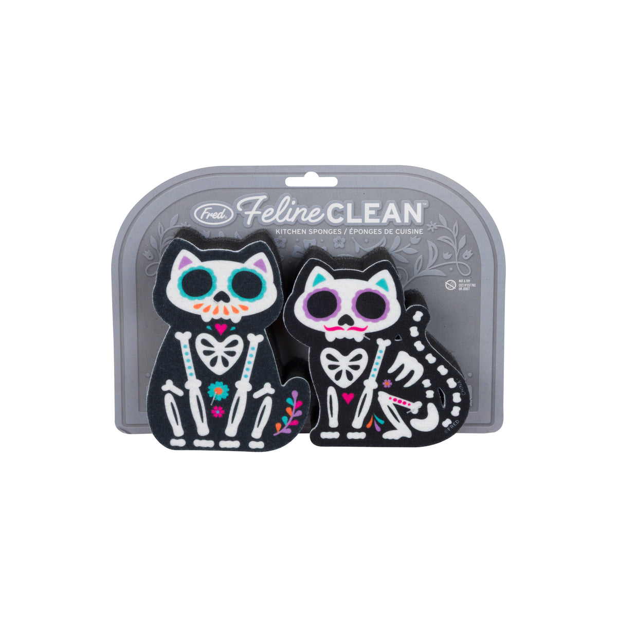 Two Feline Clean cat-shaped kitchen sponges in black with Day of the Dead sugar skull designs, displayed in their gray retail blister packaging on a white background.