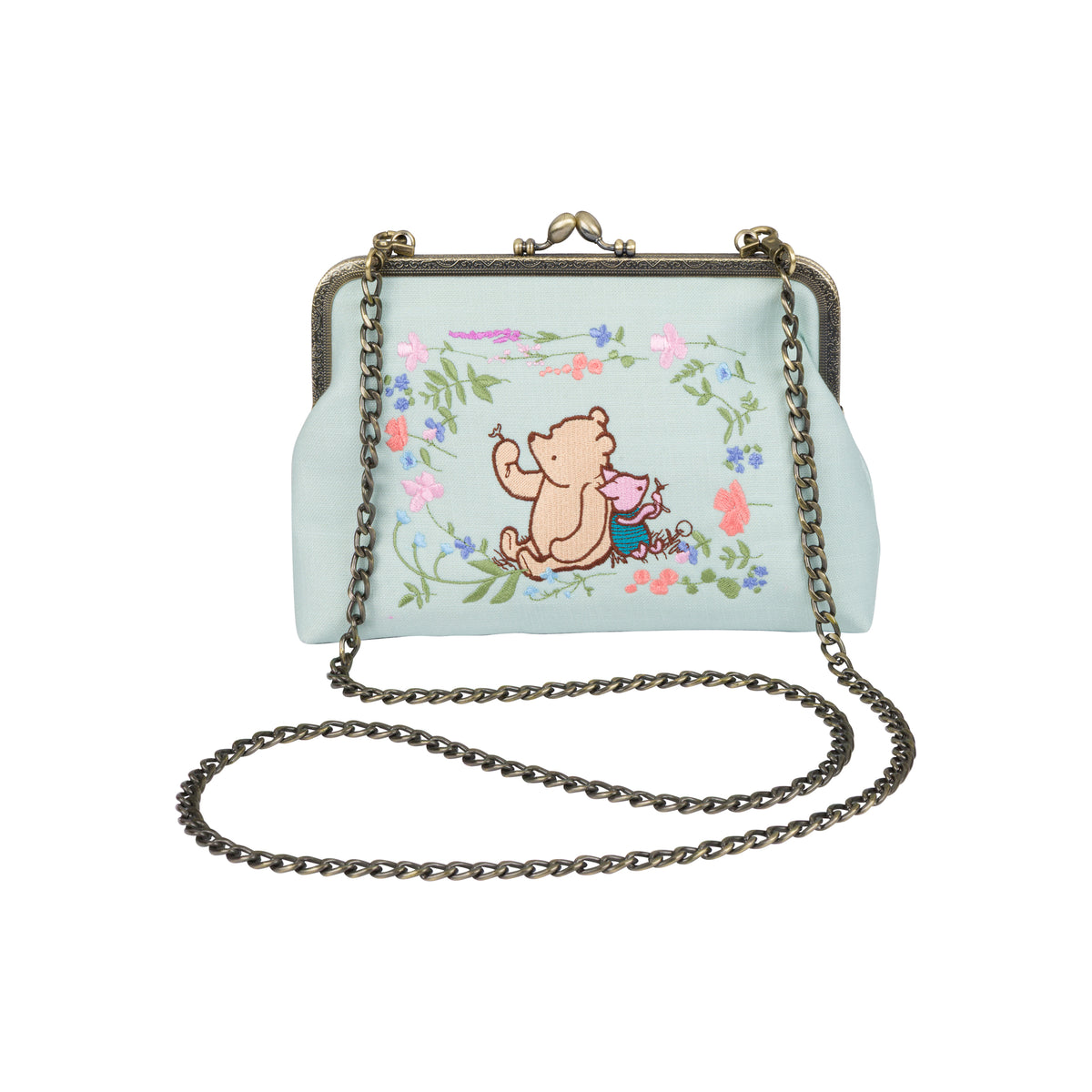 A light blue kiss-lock handbag featuring a cartoon illustration of Winnie the Pooh and a pink pig in a floral border, with a dark metal chain strap.