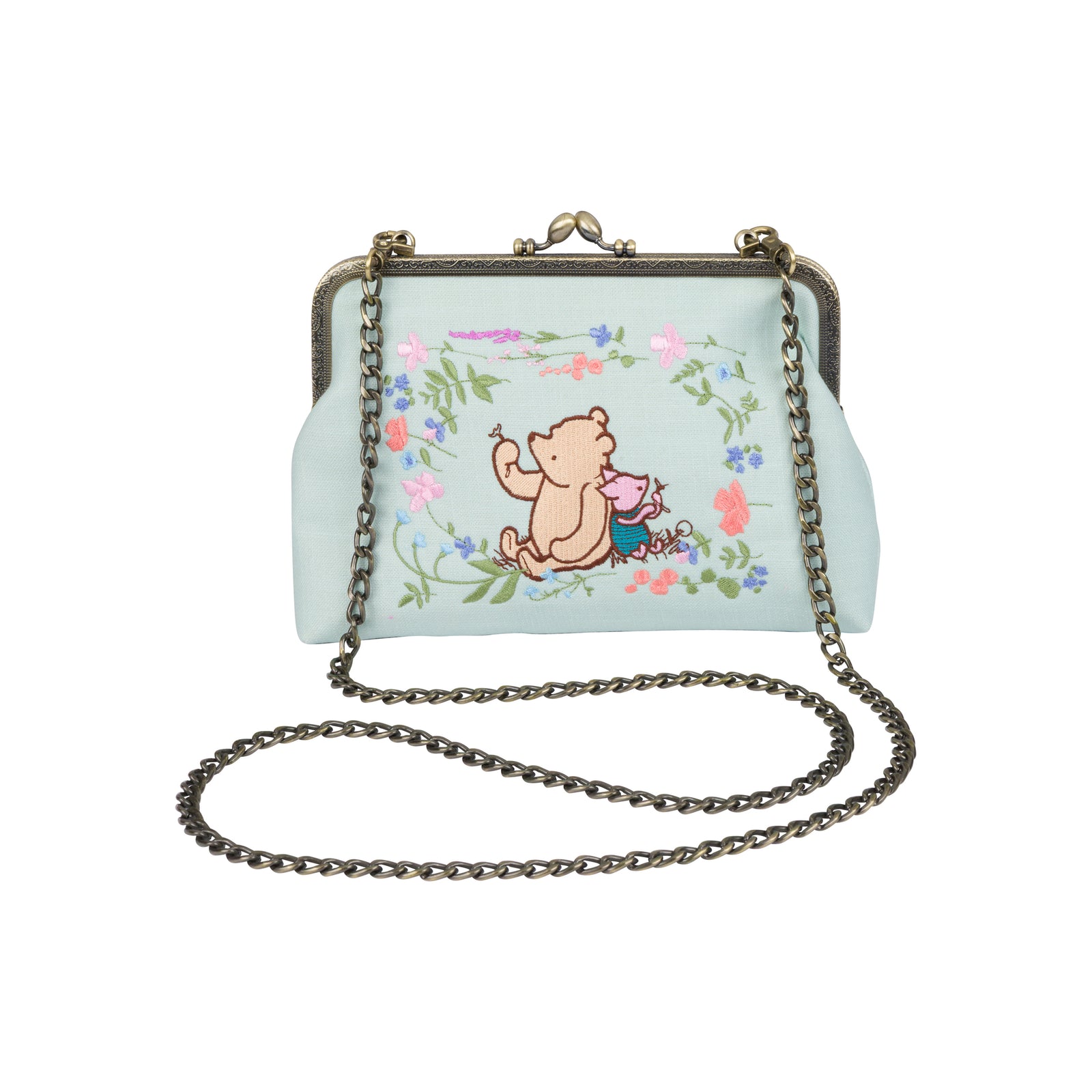A light blue kiss-lock handbag featuring a cartoon illustration of Winnie the Pooh and a pink pig in a floral border, with a dark metal chain strap.