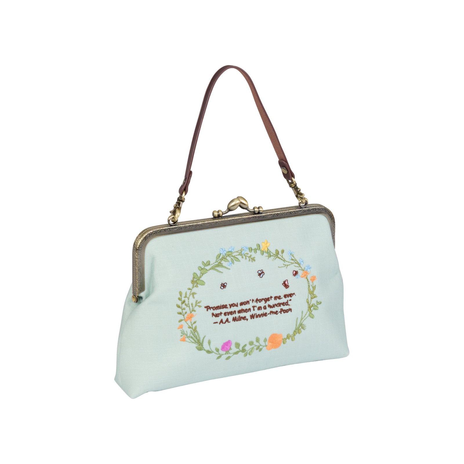 A light blue kiss-lock handbag featuring a cartoon illustration of Winnie the Pooh and a pink pig in a floral border, with a dark metal chain strap.