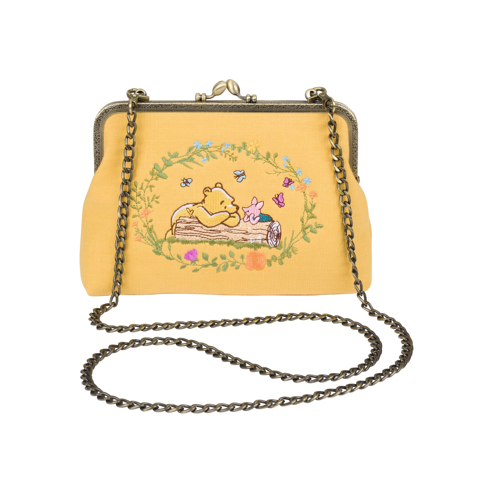 A yellow kiss-lock handbag featuring an embroidered illustration of Winnie the Pooh and Piglet in a floral wreath, with a dark metal chain strap and clasp.