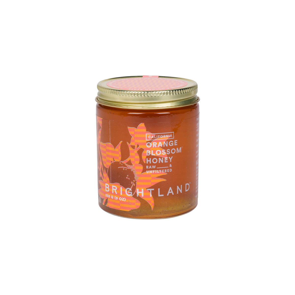 A glass jar of Brightland California Orange Blossom Honey with a gold metal lid, set against a solid white background.