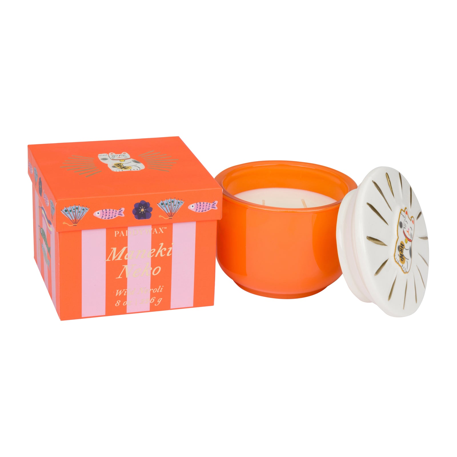 An orange glass jar candle with its white lid leaning against it, shown next to its orange and pink branded box on a plain white background.