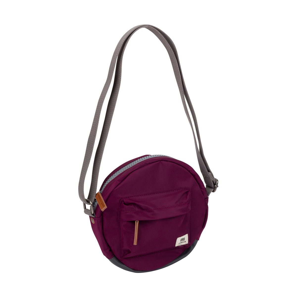 A small round crossbody bag in deep burgundy with a gray strap, featuring a front zippered pocket and a small white brand label, shown on a plain white background.