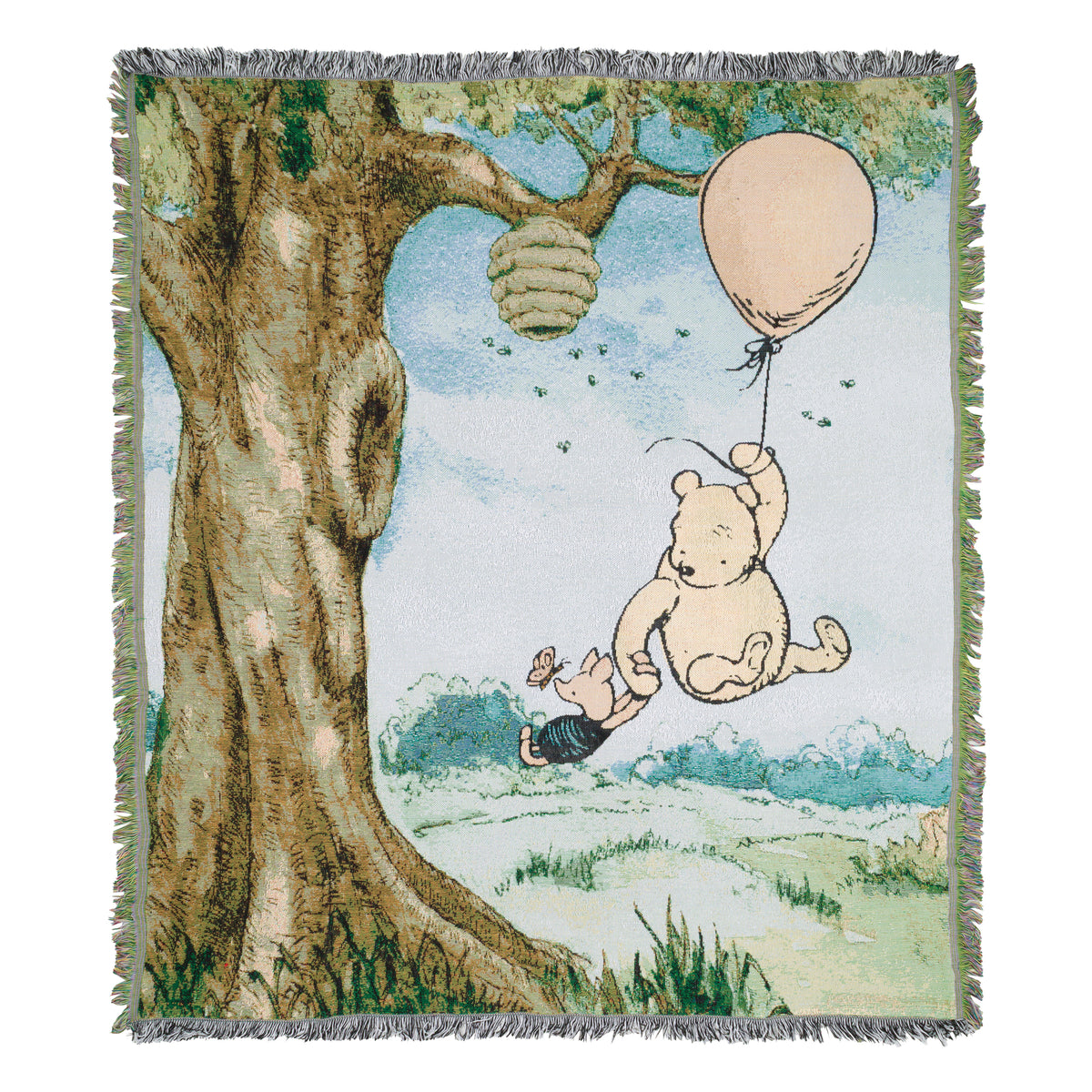 A woven throw blanket featuring Winnie the Pooh and Piglet hanging from a balloon tree, with a large tree trunk, bees, and fringed edges.