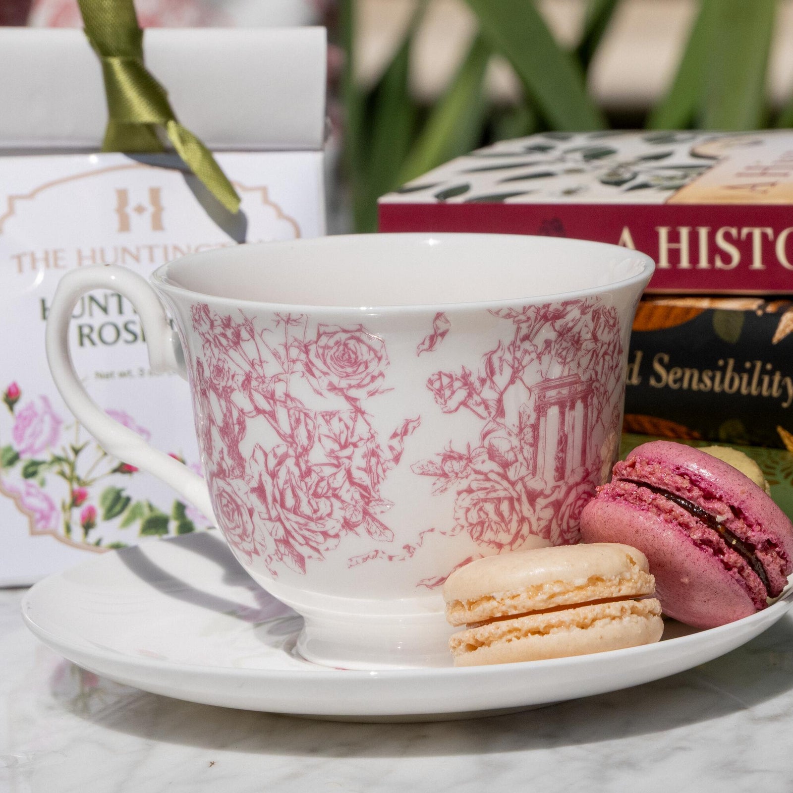 A white bone China teacup and saucer with a red floral toile print.