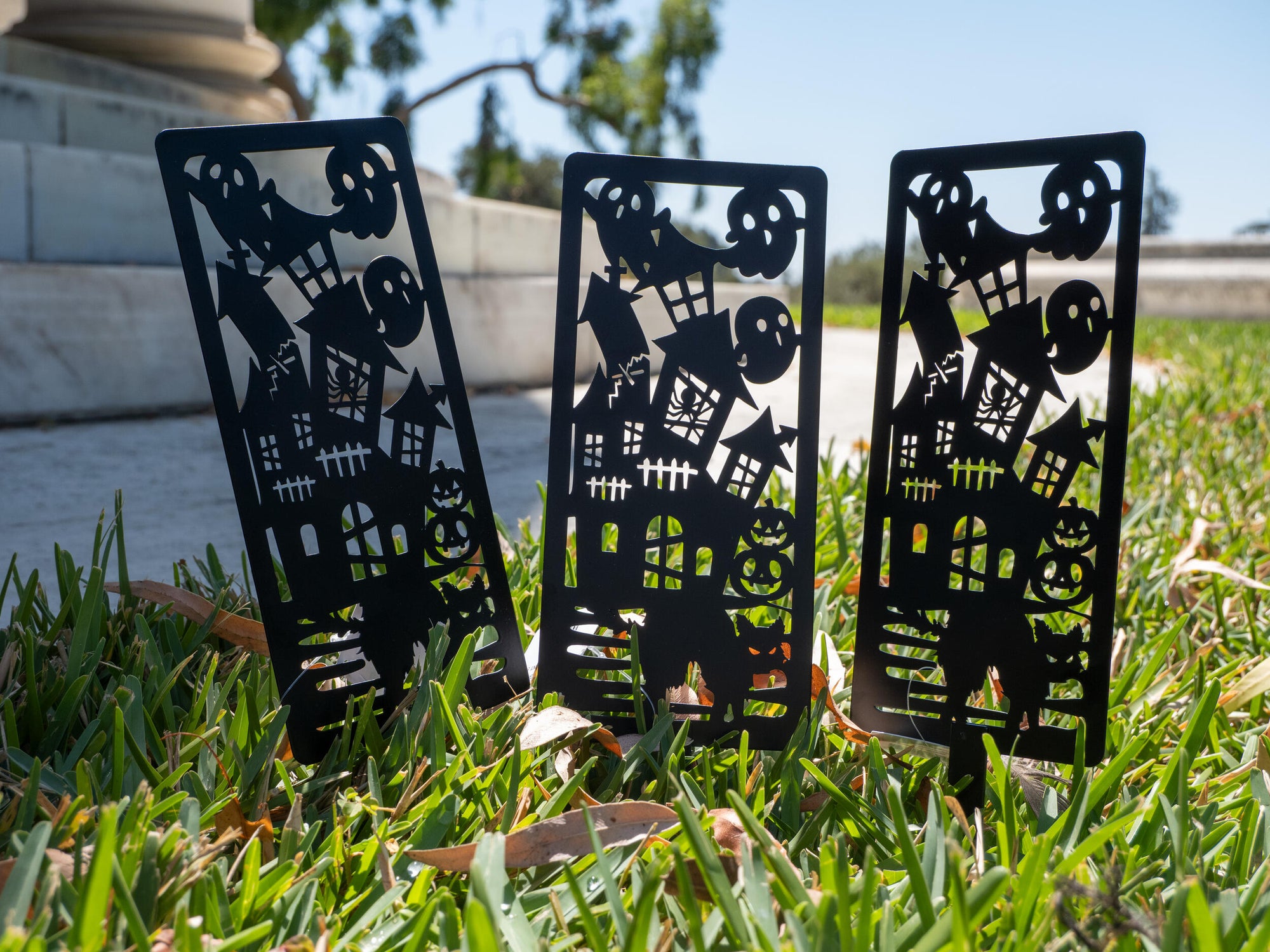 Three black metal garden art pieces with Halloween-themed cutouts on a white background.