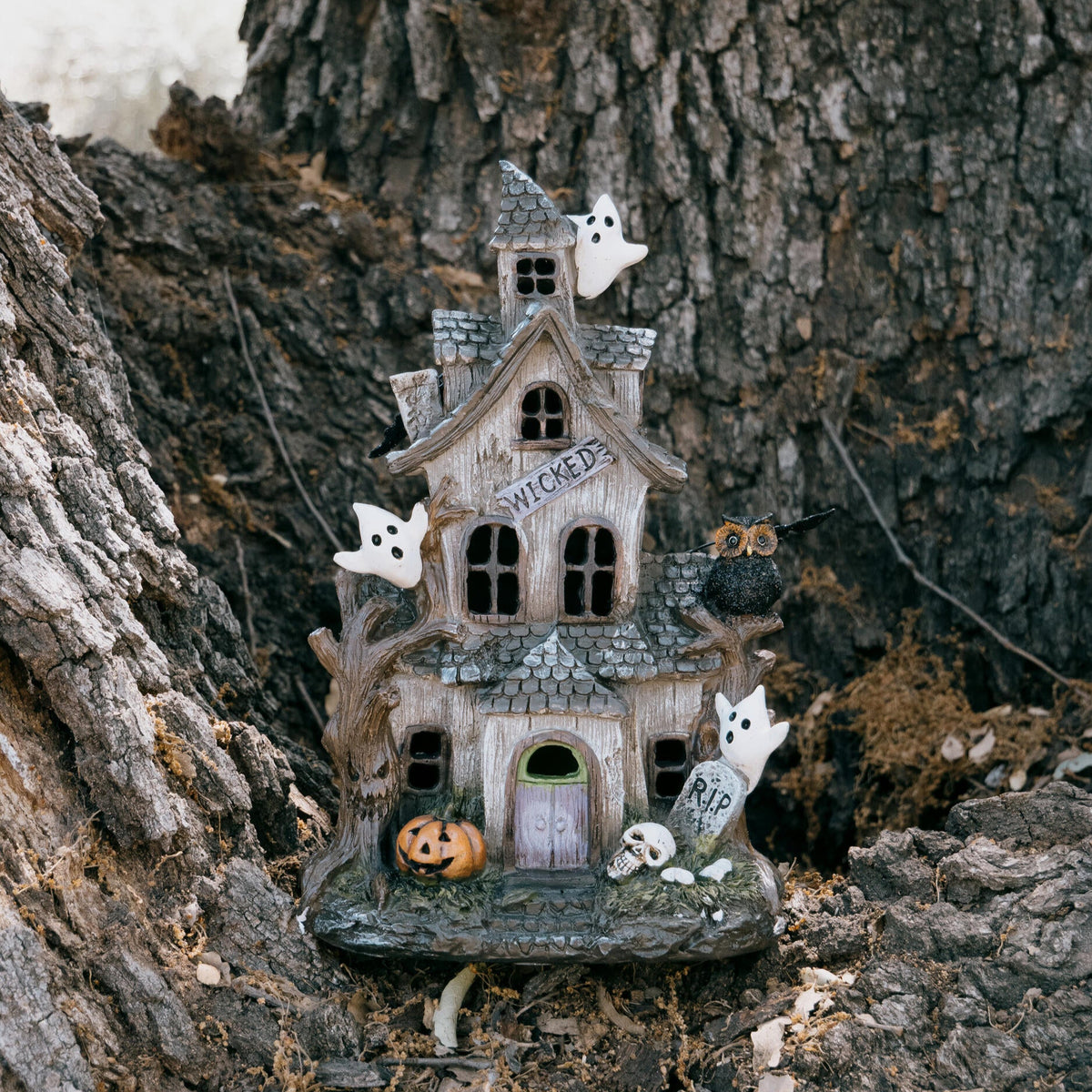 Small Halloween-themed house with ghosts and pumpkins on a tree trunk