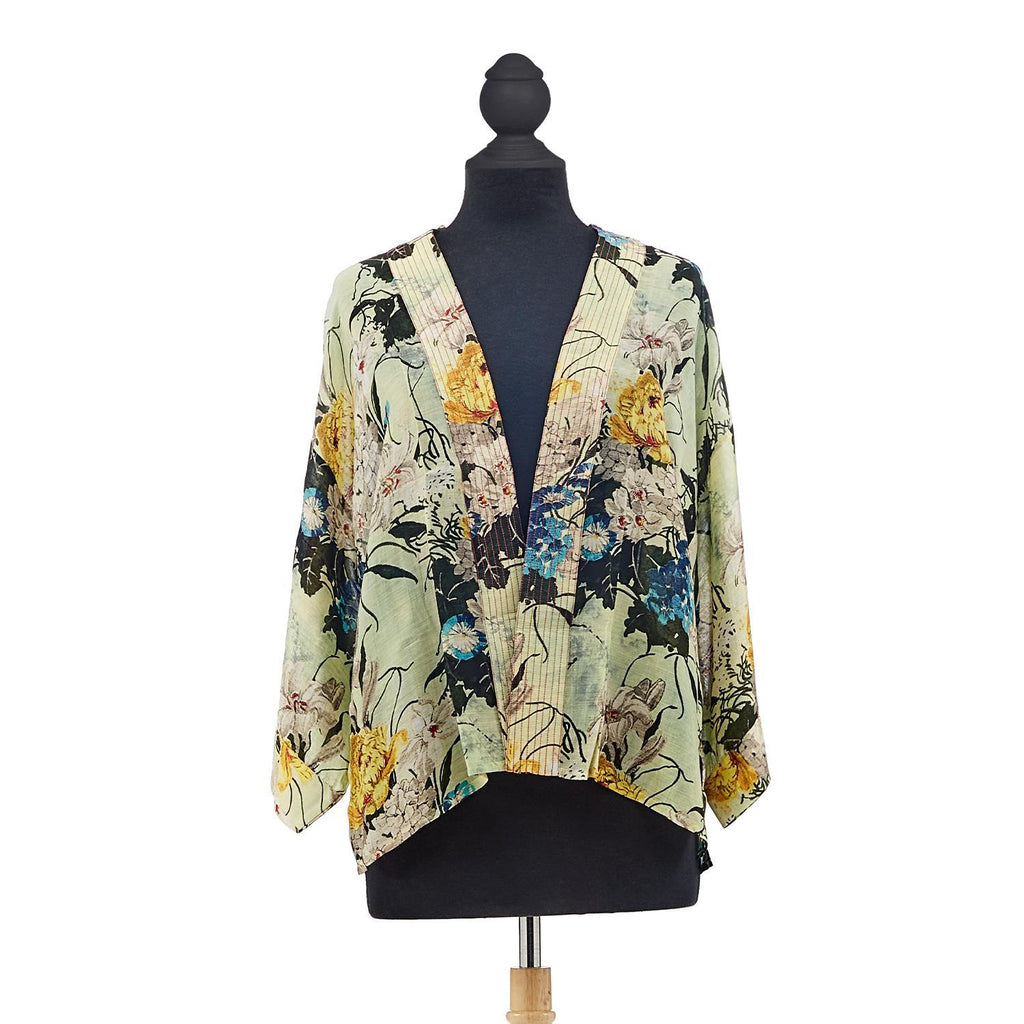 Beautiful, vibrant winter lilies burst into bloom on a soft pale green base, on this ultra wearable, soft, silk-like short kimono. This one-size, loose-fitting kimono style jacket has ¾ length sleeves, an open front and a lightly embroidered lapel. One Size. 50% modal & 50% viscose.