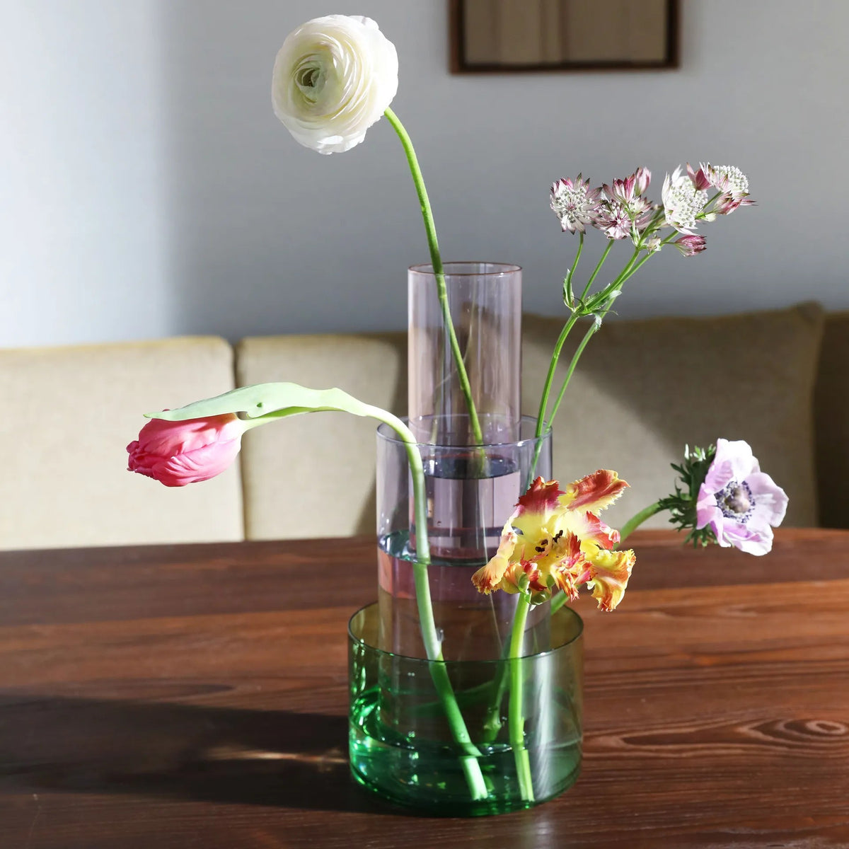 Clear and green glass vase with flowers on a wooden table