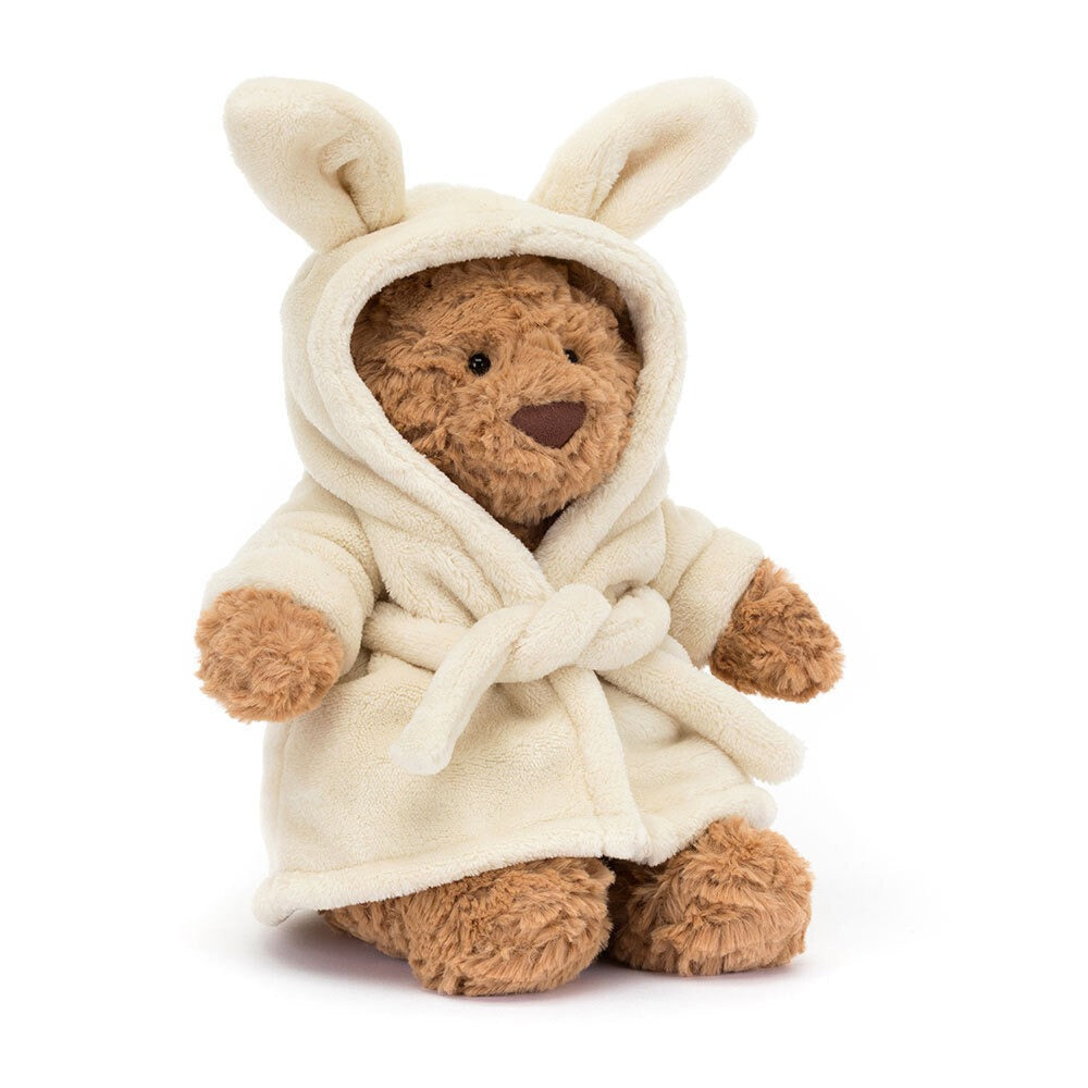 Jellycat Bartholomew bear plush toy wearing a cream robe with bunny ears on a white background