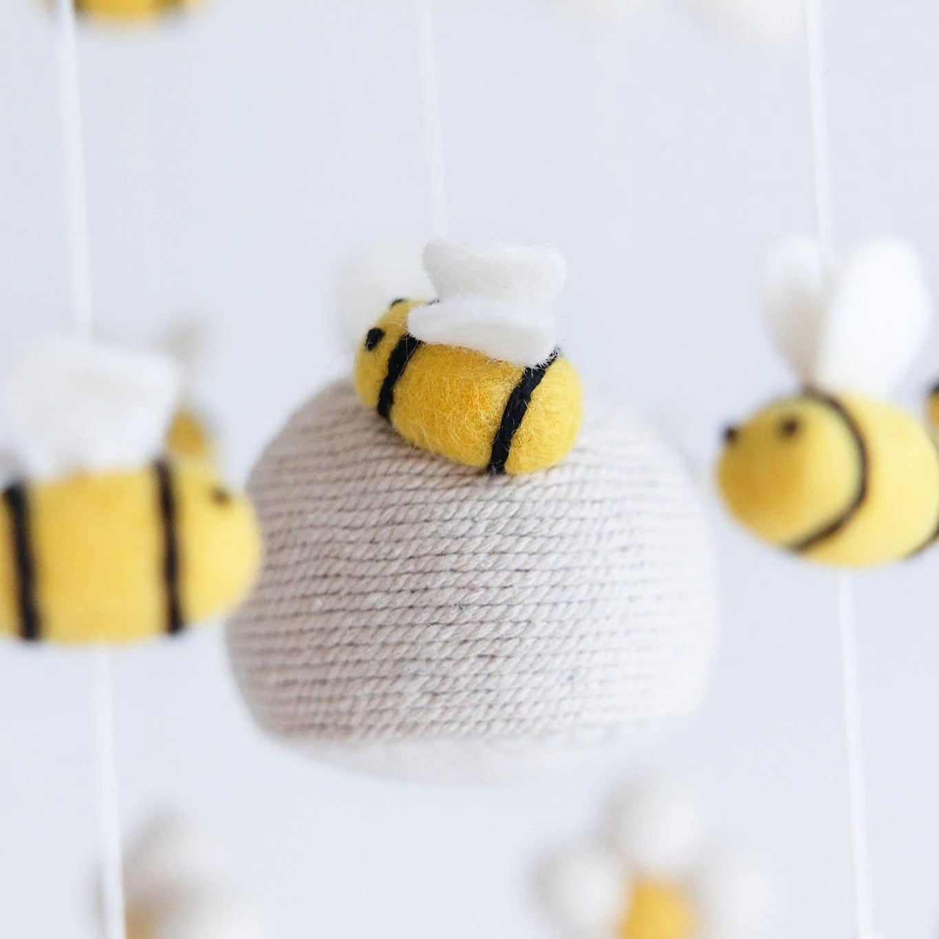 Baby mobile with flowers, bees, and a beehive on a white background