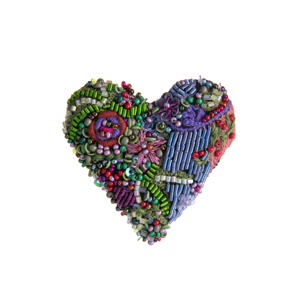 This beautifully detailed, nature inspired hand-made heart pin features intricate beading and embroidery on a base of cotton and felt. Add this pin to a simple outfit to add a splash of detail and color. Hand-made, limited-edition pin Materials: Cotton, felt, embroidery, beading. Dimensions: 1.75" x 1.5".