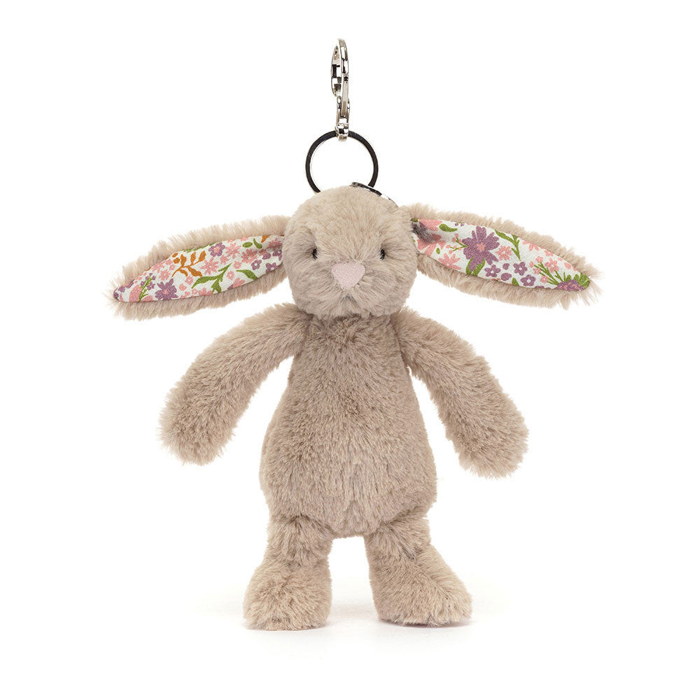 Blossom Beige Bunny Bag Charm has brought along some special flowers to brighten your day! In iconic Bashful beige fur with a cream bobtail, this pocket-sized Blossom Beige Bunny has soft cotton floral ears, printed with an original Jellycat design of pink and purple flowers. With a silver clasp to attach to any bag, this bunny brings the joy! Dimensions: 7.1" x 2"x 1.6". 