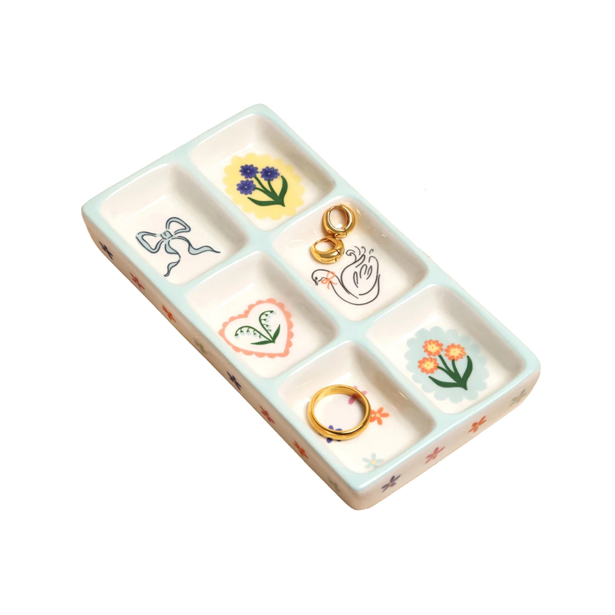 Ceramic trinket tray with six compartments and illustrations of flowers, bows, a heart and a swan, with a light blue trim, on a white background.