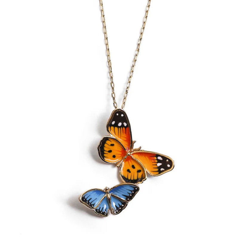Butterfly-shaped pendant on a gold chain against a white background