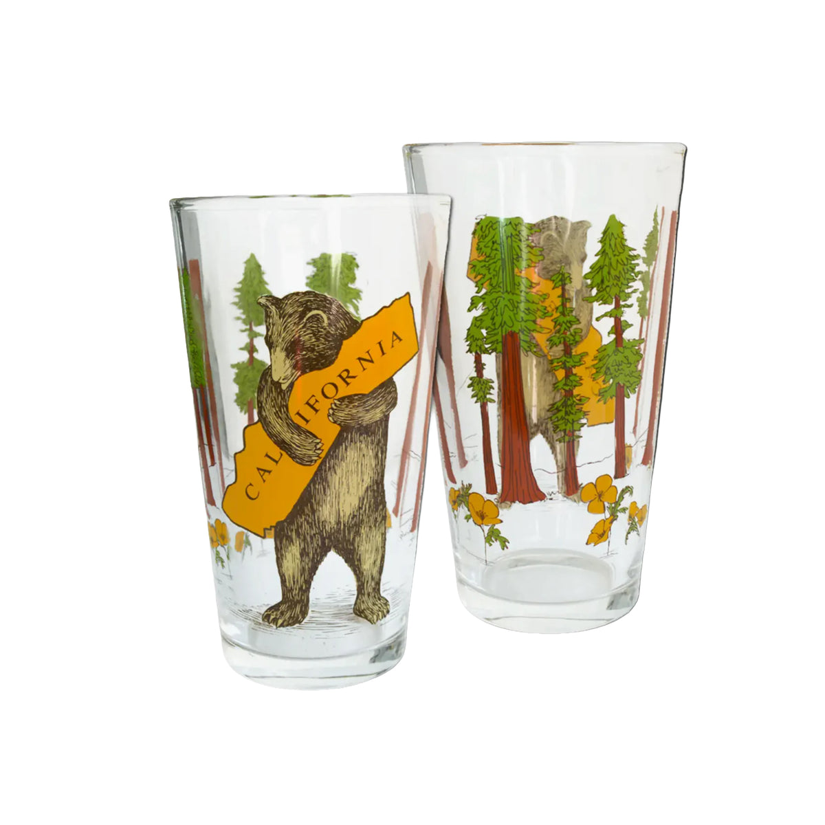 Two clear glass pint glasses with forest illustrations. The front glass shows a brown bear holding a yellow sign that reads 'CALIFORNIA,' while the back glass shows a forest scene with trees and yellow flowers.