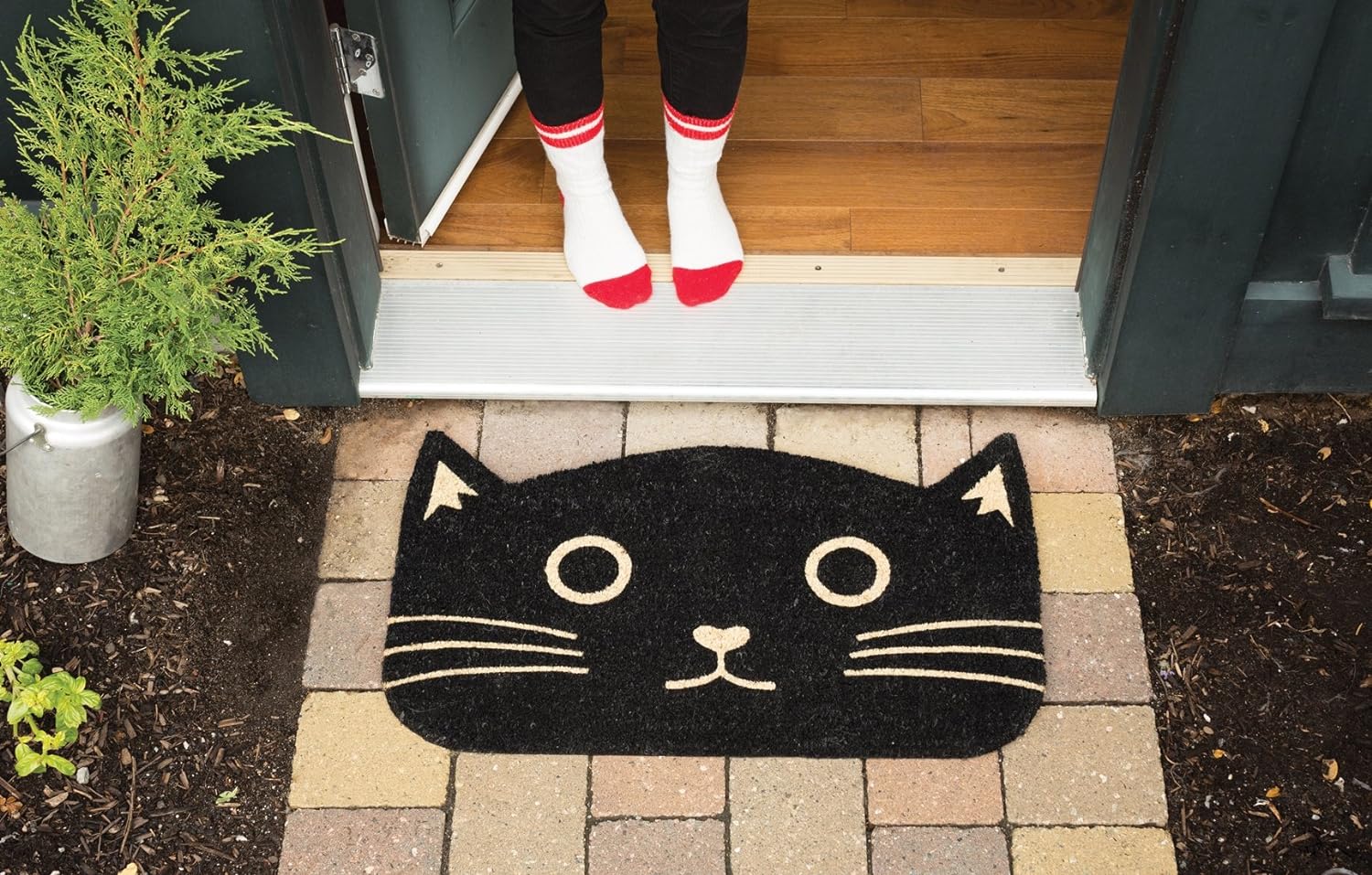 Black cat-shaped doormat with beige accents on a white background