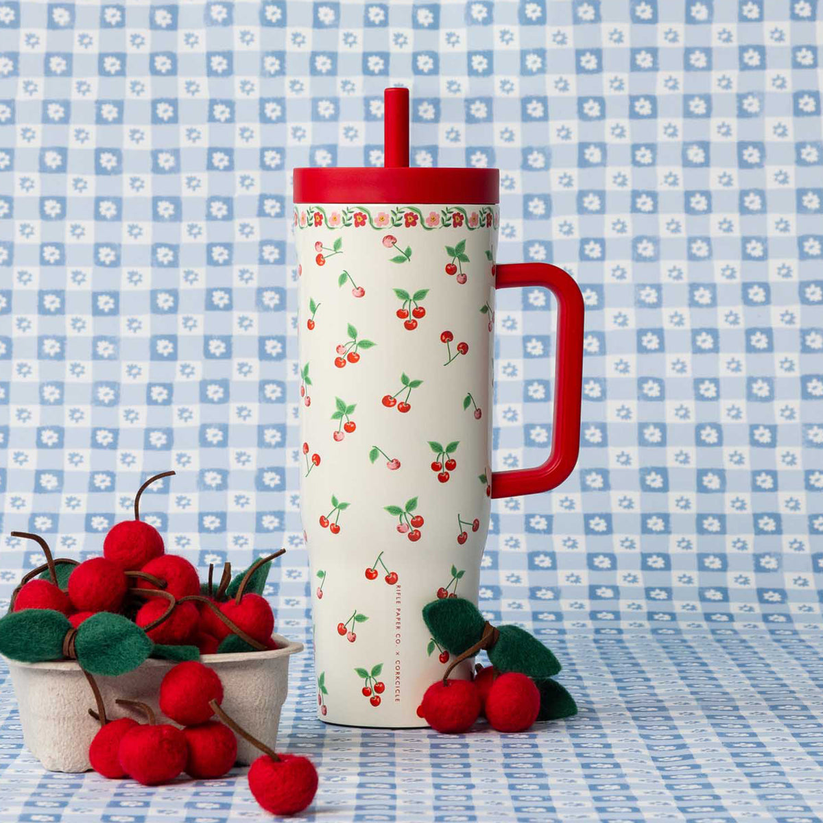 Tumbler with cherry design on a blue floral patterned background